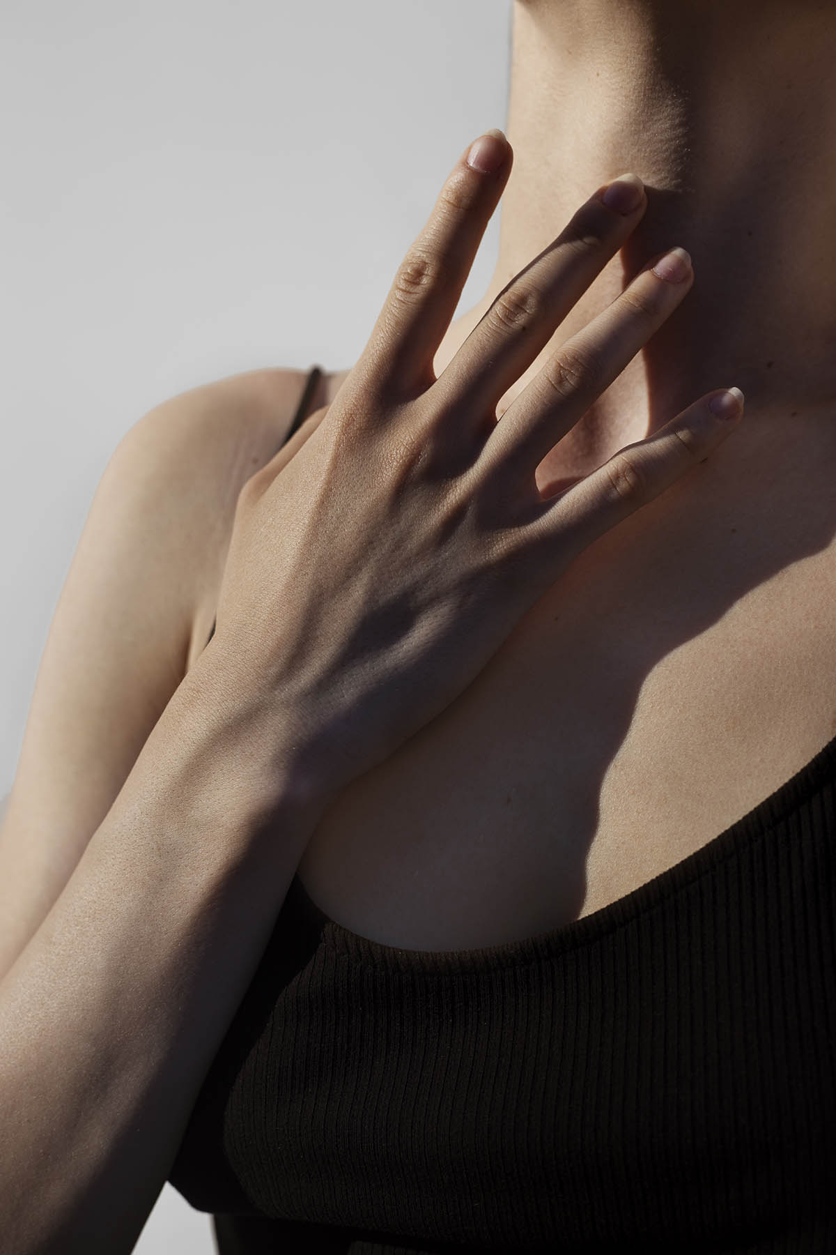 Девушка прикасается своими руками к шее